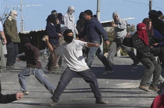 Masked Jewish settlers throw stones at Palestinian houses in the West Bank city of Hebron, Tuesday, Dec. 2, 2008. Dozens of Jewish settlers rioted Tuesday in the West Bank town of Hebron, clashing with the Israeli troops who guard them but who may also soon evict them from a disputed building they