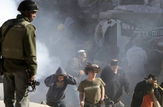 Jewish settlers run for cover after Israeli border police threw a stun grenade towards them in the West Bank city of Hebron December 2, 2008. Jewish settlers and Palestinians threw stones in clashes on Monday that injured five in Hebron where Jews want to stop the eviction of 13 settler families, witnesses said. From Reuters Pictures by REUTERS.