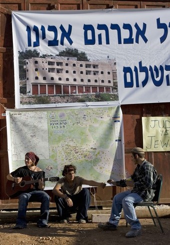 Jewish settlers play guitar in front of a disputed house occupied by settlers in the divided West Bank city of Hebron on November 23, 2008. About 100 Jewish settlers last week defied a High Court order to evacuate the house in the flashpoint West Bank city of Hebron, and braced for possible confrontation with police. The court rejected an appeal by two rightwing organisations against an order issued by the state to evacuate the Hebron house, which the settlers claim they had purchased from a Palestinian, who denies selling the house. The controversial house was occupied by dozens of hardline Jewish settlers in March 2007. They have remained in the four-storey building which they dubbed 
