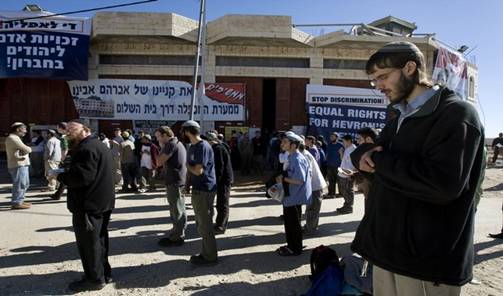 Israeli settlers pray outside a disputed house in the flashpoint West Bank city of Hebron on December 3, 2008. Israeli settlers and hundreds of supporters prepared today to battle a forceful eviction after Israel declared a closed military area around the house in Hebron, occupied in defiance of a court order. The controversial house was occupied by dozens of hardline Jewish settlers in March 2007 and they have remained in the building despite a November 16 Israeli High Court court order for them to move out. The settlers say they bought the house from a Palestinian, who denies that a deal was ever completed. From Getty Images by AFP/Getty Images.