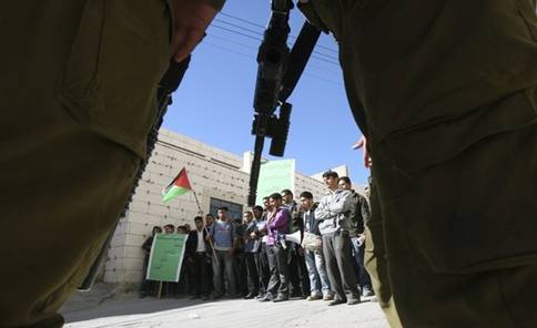 An Israeli soldier stands guard (front) as Palestinians protest against Jewish settlers in the West Bank city of Hebron, December 3, 2008. Jewish settlers and Palestinians threw stones in clashes on Monday that injured five in the West Bank city of Hebron where Jews want to stop the eviction of 13 settler families, witnesses said. From Reuters Pictures by REUTERS.